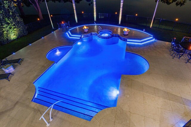 pool at twilight with a patio area