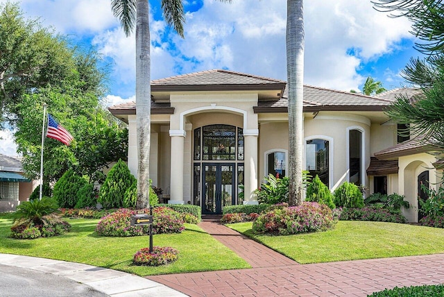 view of front facade with a tile roof, a front lawn, and stucco siding