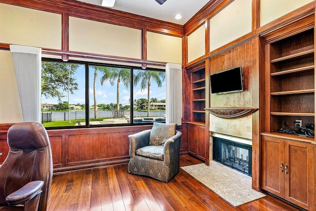 interior space featuring built in shelves, ornamental molding, dark wood finished floors, and a high end fireplace