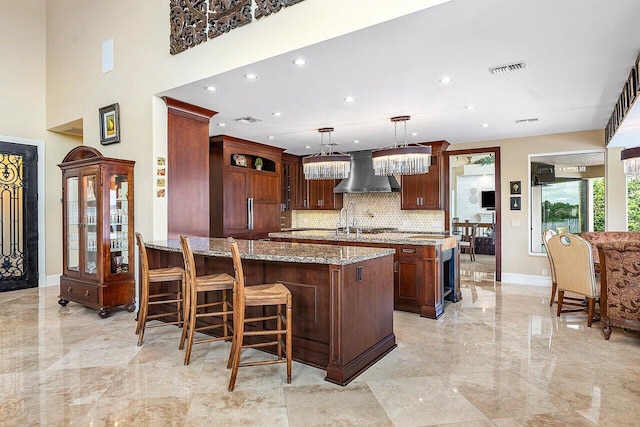 kitchen featuring light stone countertops, a peninsula, marble finish floor, a center island, and wall chimney exhaust hood