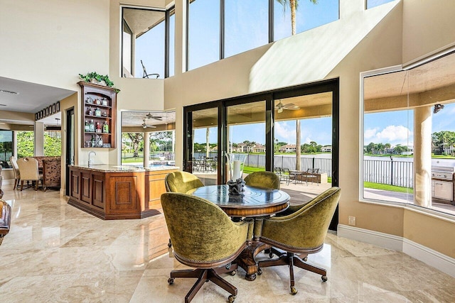 tiled dining space with sink, ceiling fan, and a towering ceiling