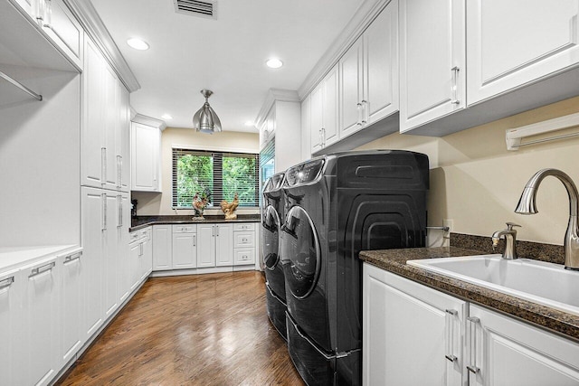 clothes washing area with cabinet space, visible vents, dark wood-style flooring, separate washer and dryer, and a sink