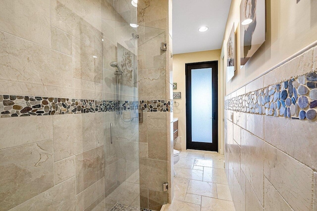 full bathroom featuring a stall shower, stone tile floors, toilet, tile walls, and recessed lighting