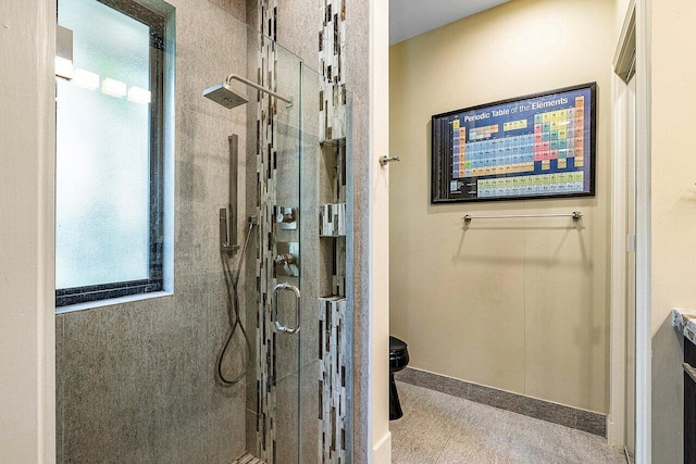 full bathroom with a shower stall and baseboards