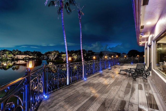 deck at night featuring a water view