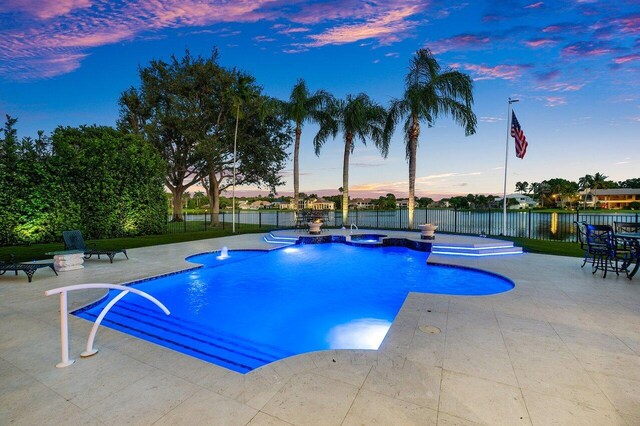 pool at dusk with a patio area and pool water feature