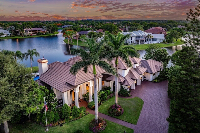 aerial view at dusk with a water view and a residential view