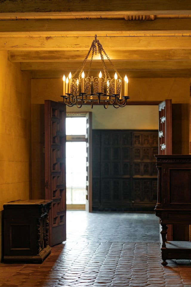 interior space with beam ceiling, a notable chandelier, and wood finished floors