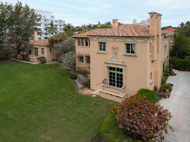 back of house featuring stucco siding, a tile roof, and a yard