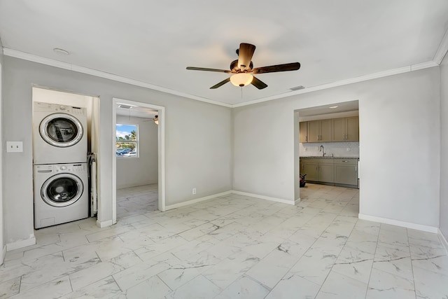 laundry room featuring crown molding, ceiling fan, stacked washer / dryer, and sink