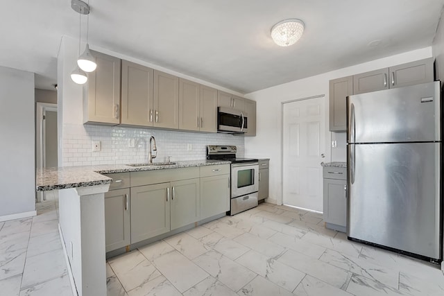 kitchen featuring sink, hanging light fixtures, appliances with stainless steel finishes, kitchen peninsula, and light stone countertops