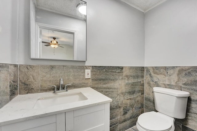 bathroom with tile walls, vanity, a textured ceiling, and toilet