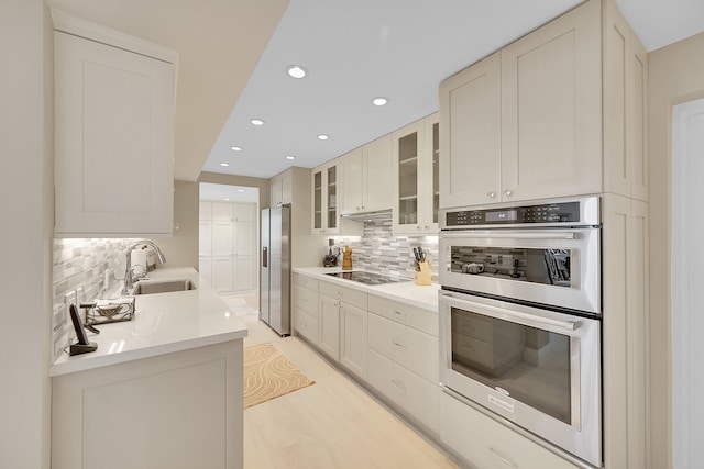 kitchen with tasteful backsplash, sink, white cabinets, and stainless steel appliances