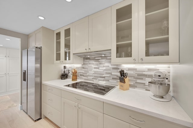 kitchen featuring black electric stovetop, stainless steel fridge with ice dispenser, and backsplash