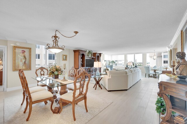 dining area with light wood-type flooring and ornamental molding