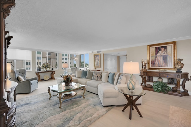 living room featuring a chandelier, light hardwood / wood-style floors, and ornamental molding