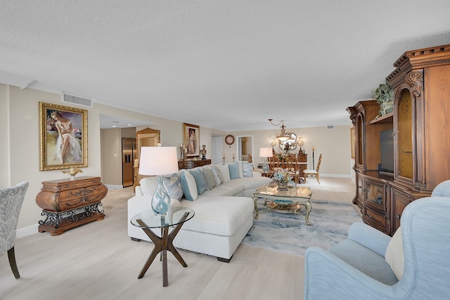 living room featuring a textured ceiling, light hardwood / wood-style flooring, and an inviting chandelier