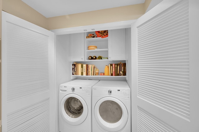 laundry room with washing machine and clothes dryer and cabinets