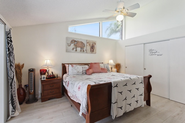 bedroom with ceiling fan, a closet, light wood-type flooring, and vaulted ceiling