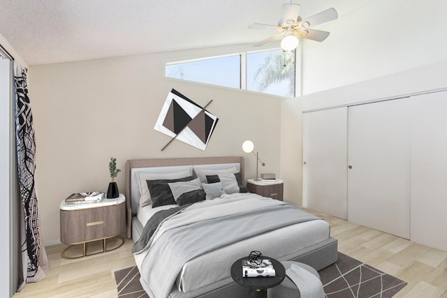 bedroom with ceiling fan, a textured ceiling, lofted ceiling, a closet, and light wood-type flooring