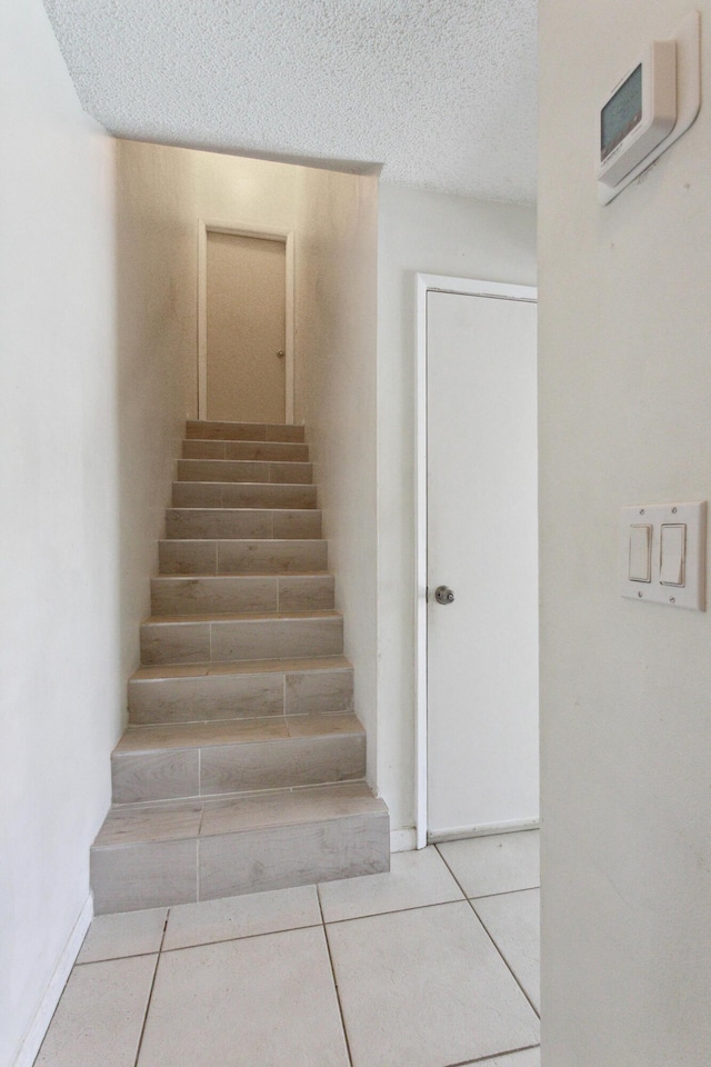 stairway with tile patterned flooring and a textured ceiling