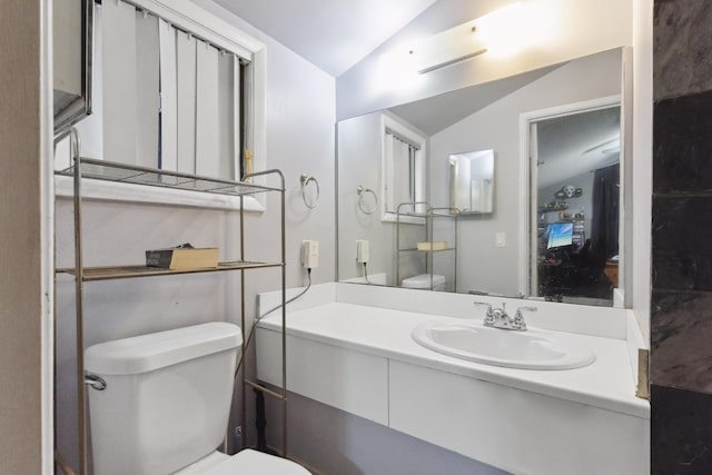 bathroom featuring toilet, vanity, and vaulted ceiling