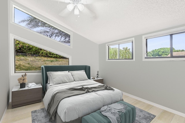 bedroom featuring a textured ceiling, light hardwood / wood-style floors, vaulted ceiling, and ceiling fan