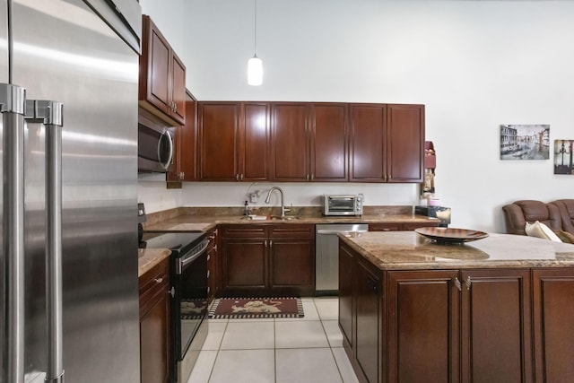 kitchen featuring stainless steel appliances, sink, pendant lighting, a kitchen island, and light tile patterned flooring