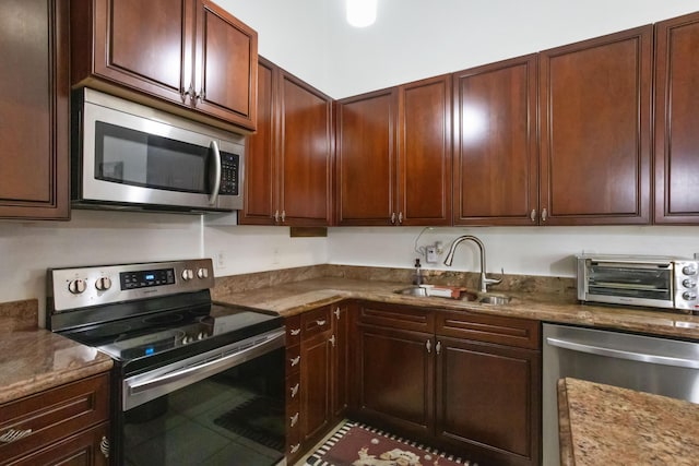 kitchen with light stone countertops, sink, and appliances with stainless steel finishes