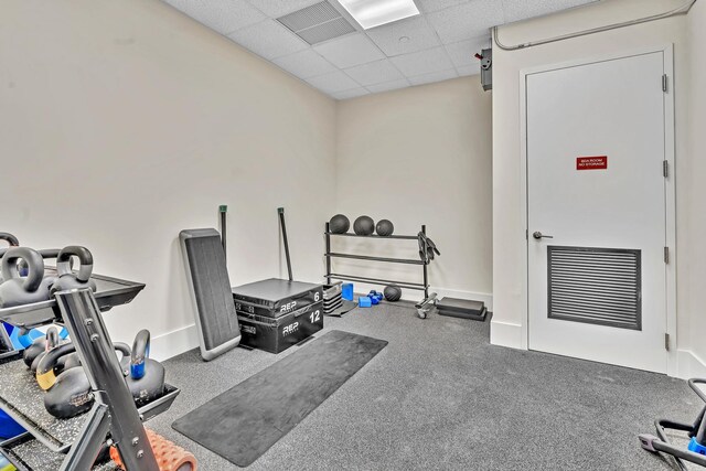 workout room featuring a paneled ceiling and carpet