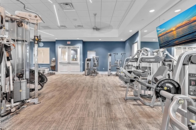 workout area featuring carpet, a tray ceiling, a ceiling fan, a drop ceiling, and baseboards