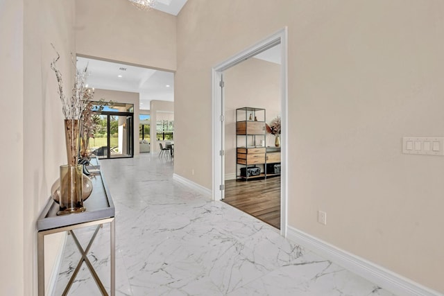 hall featuring marble finish floor, baseboards, a notable chandelier, and recessed lighting