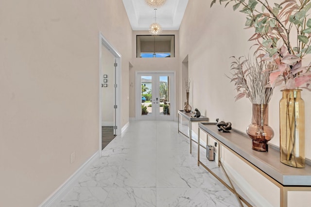 entryway featuring french doors, light tile patterned floors, a raised ceiling, and a towering ceiling