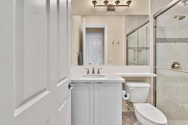 bathroom featuring tile patterned flooring, vanity, toilet, and walk in shower