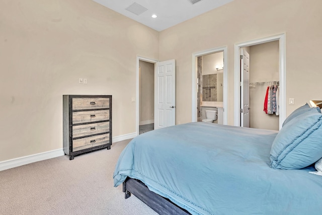 bedroom featuring ensuite bathroom, a spacious closet, light colored carpet, and a closet