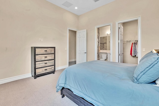 carpeted bedroom with ensuite bathroom, recessed lighting, visible vents, baseboards, and a spacious closet