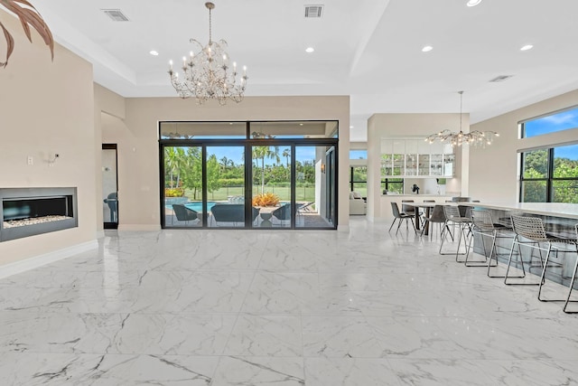 living area featuring a glass covered fireplace, visible vents, and an inviting chandelier