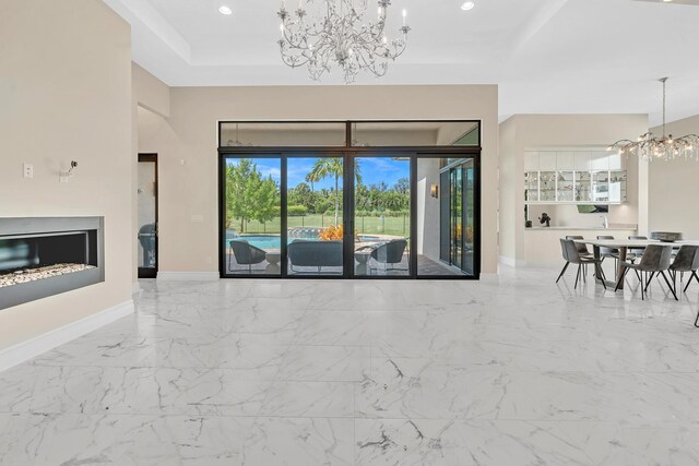 unfurnished living room with a tray ceiling, light tile patterned floors, and a chandelier