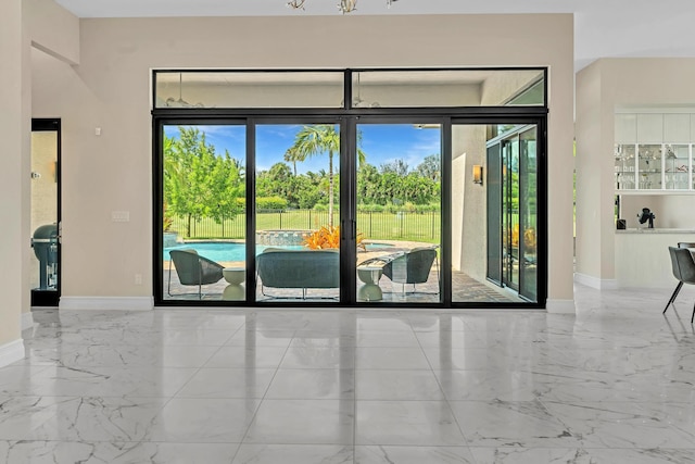 doorway to outside featuring marble finish floor and baseboards