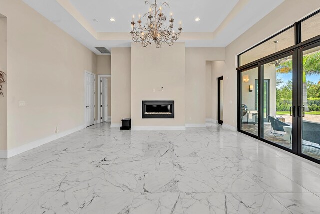 unfurnished living room featuring light tile patterned floors, an inviting chandelier, a raised ceiling, and french doors