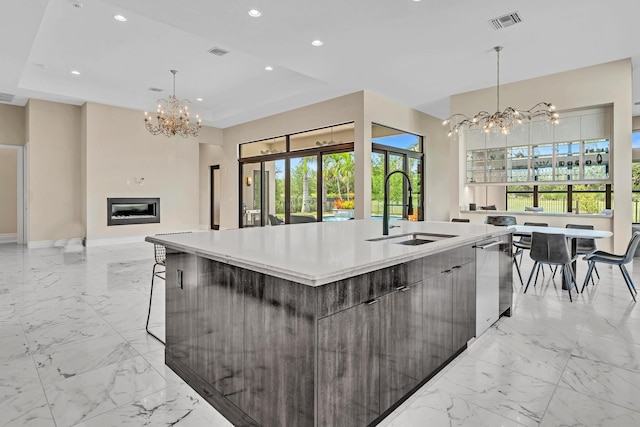 kitchen featuring dishwasher, modern cabinets, marble finish floor, an inviting chandelier, and a sink