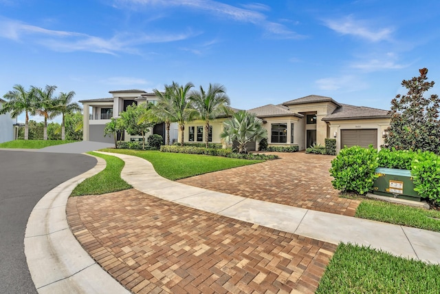 prairie-style house featuring decorative driveway, stucco siding, a garage, a tiled roof, and a front lawn