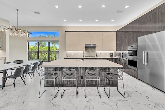 kitchen featuring visible vents, modern cabinets, appliances with stainless steel finishes, a breakfast bar area, and under cabinet range hood