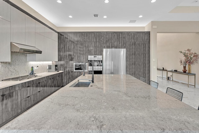 kitchen featuring under cabinet range hood, a sink, marble finish floor, appliances with stainless steel finishes, and modern cabinets