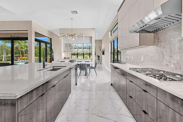 kitchen featuring an inviting chandelier, pendant lighting, stainless steel gas stovetop, extractor fan, and sink