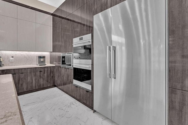 kitchen featuring marble finish floor, light countertops, appliances with stainless steel finishes, dark brown cabinets, and modern cabinets