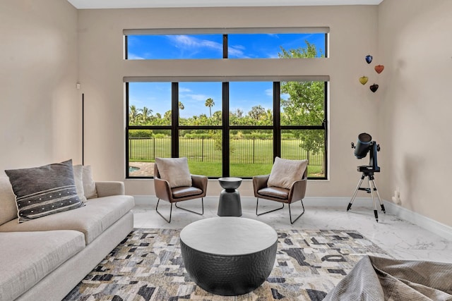 living area with marble finish floor, plenty of natural light, and baseboards