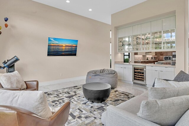 living room featuring beverage cooler, baseboards, marble finish floor, indoor wet bar, and recessed lighting