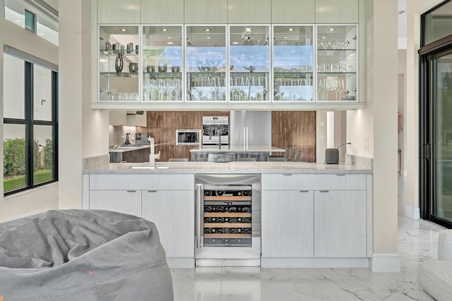 bar with marble finish floor, beverage cooler, and a sink