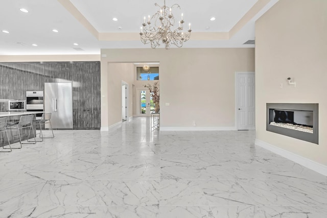 unfurnished living room featuring a chandelier, a tray ceiling, and light tile patterned flooring